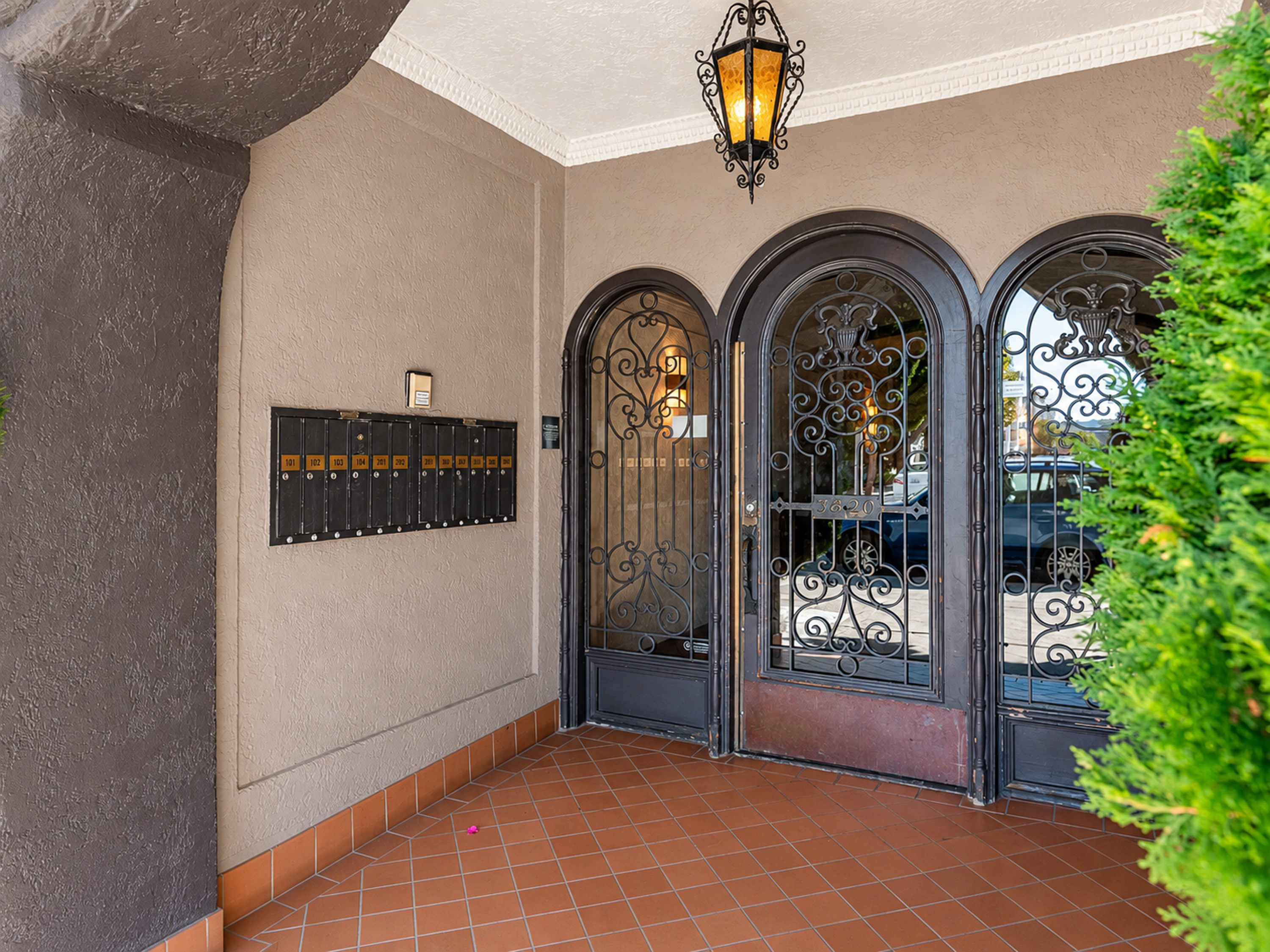 A building entrance with a black gate and a lantern hanging from the ceiling.